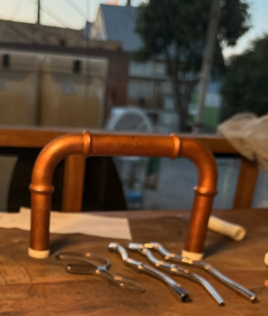 Copper pipe and tools laid out on a worn plumber's workbench at dusk